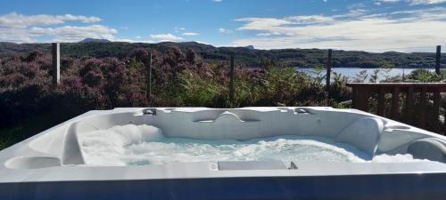 a bath tub sitting on top of a deck at Caisteal Liath House in Lochinver