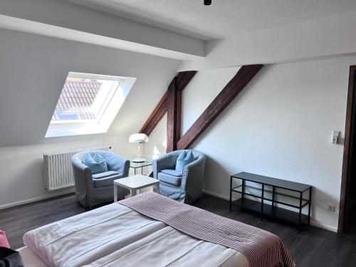 a bedroom with two chairs and a bed and a window at Hotel Restaurant Goldenes Ross in Göllheim