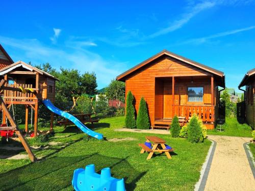a playground with a wooden house and a slide at ALBATROS Wicie in Wicie