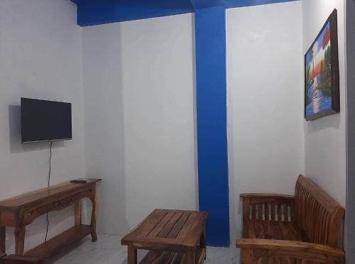Habitación con 2 bancos de madera y TV en la pared. en Baguio La Famille Residences, en Baguio
