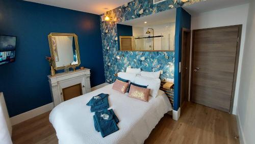 a bedroom with a bed with blue walls and a mirror at La Belle Epoque & Spa - Maison d'hôtes in Cournon-dʼAuvergne