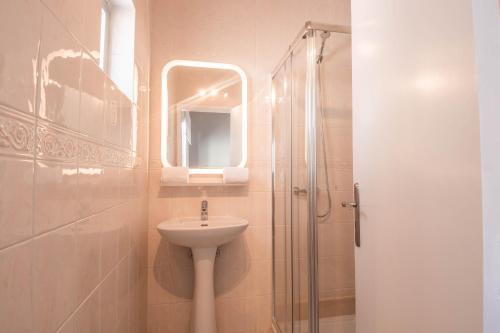 a bathroom with a sink and a shower with a mirror at Virginia Guest House in Lagoa