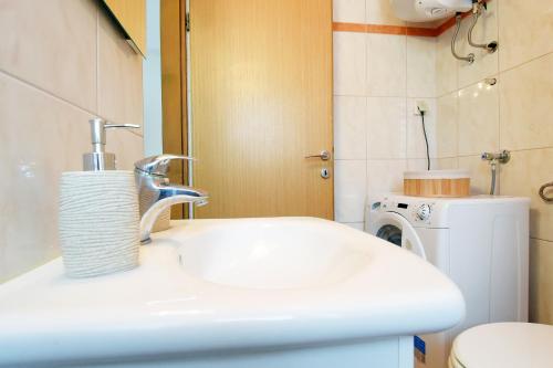 a bathroom with a sink and a washing machine at Apartman Barkunada in Vodnjan