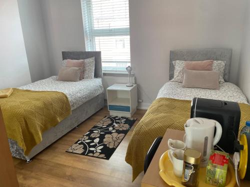 Un dormitorio con 2 camas y una mesa con una bandeja de comida. en Protea Homestay, en Mánchester