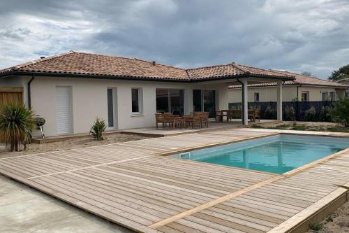 une maison avec une piscine et une terrasse en bois dans l'établissement Pavillon au bord de l'océan, à Vensac