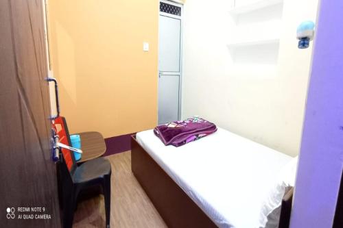 a small room with a bed with a purple bag on it at SPOT ON Ganguly Hotel Lodging And Fooding in Purulia