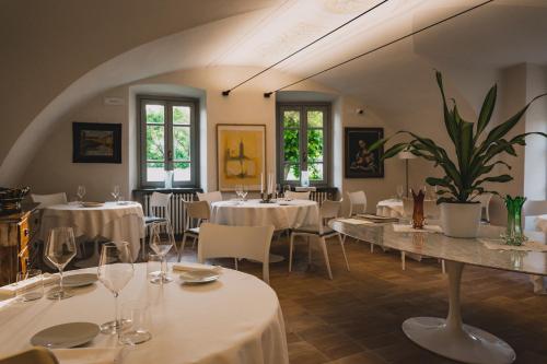 um restaurante com mesas e cadeiras brancas e janelas em VILLA MANZONI em Cologno al Serio