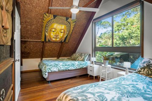 a room with two beds and a giant head on the wall at Buddha's Bungalow in Byron Bay