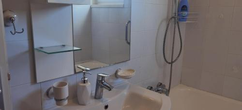 uma casa de banho branca com um lavatório e um chuveiro em DLX Apartman Adriatics em Herceg Novi