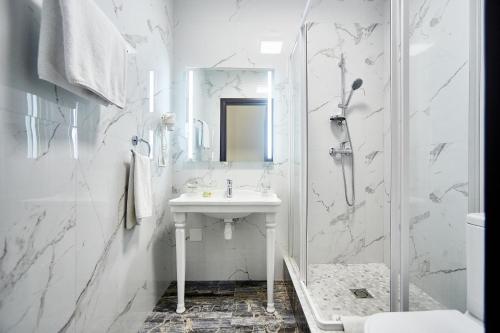 a white bathroom with a sink and a shower at Royal Street Hotel in Odesa