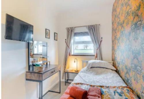 een kleine slaapkamer met een bed en een televisie bij Covehithe House-Coastal luxury- sleeps 12-with huge swimspa! in Wrentham