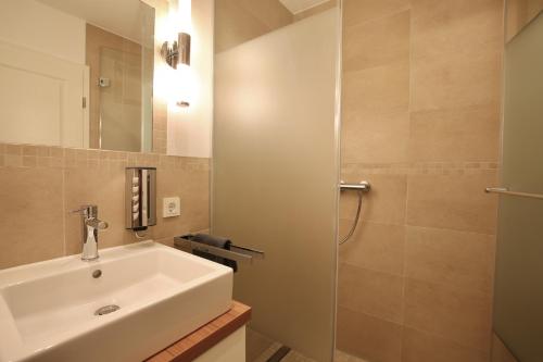 ein Bad mit einem Waschbecken und einer Dusche in der Unterkunft Villa Marina - Gigantischer Meerblick in Wangerooge