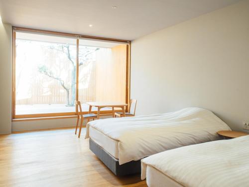 een slaapkamer met 2 bedden, een tafel en een raam bij Gyokusenkaku in Nagato