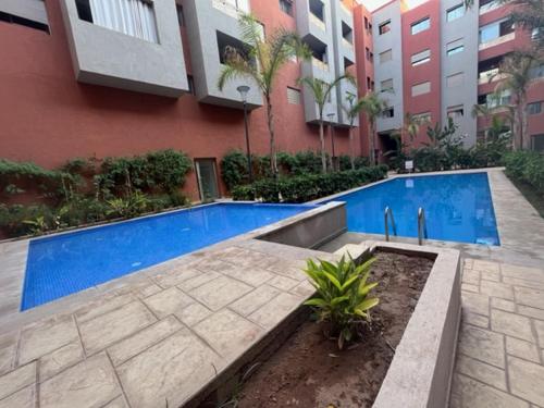 une piscine en face d'un bâtiment dans l'établissement ASAMA appartement avec piscine, à Marrakech