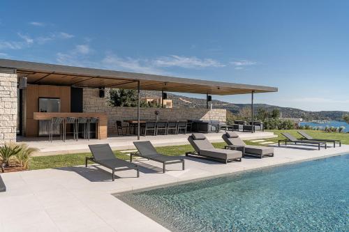een patio met stoelen en een zwembad naast een huis bij Searenity Villa in Chania