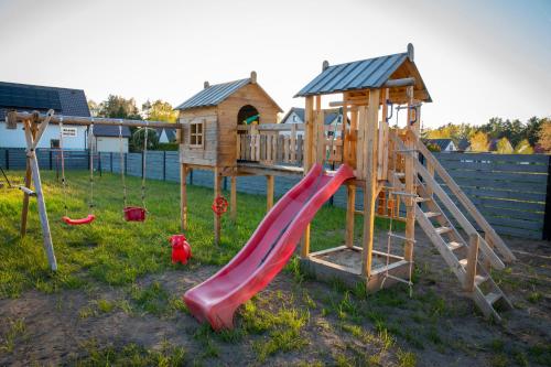 a playground with a slide and a house at Domki u Łysego in Dębki