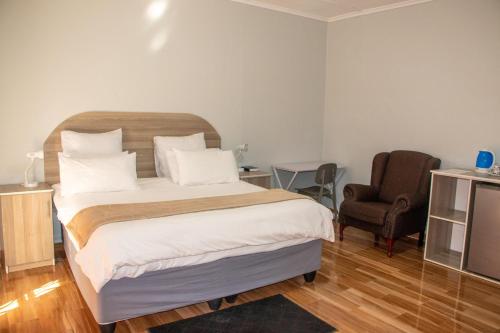 um quarto com uma cama grande e uma cadeira em Neat one bedroom in Morningside guesthouse - 2091 em Bulawayo