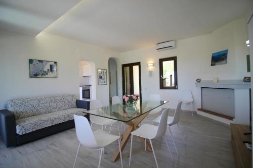a living room with a glass table and white chairs at Case vacanza Baiazzurra in Monte Nai