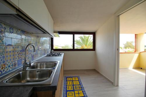 une cuisine avec un évier en acier inoxydable et une fenêtre dans l'établissement Case vacanza Baiazzurra, à Monte Nai