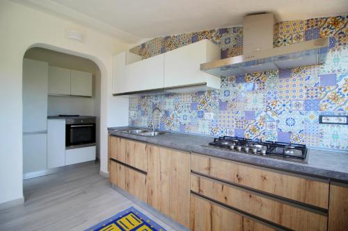 a kitchen with white cabinets and blue tiles on the wall at Case vacanza Baiazzurra in Monte Nai