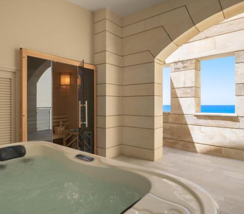 uma banheira na casa de banho com uma janela em Macaris Suites & Spa em Rethymno Town