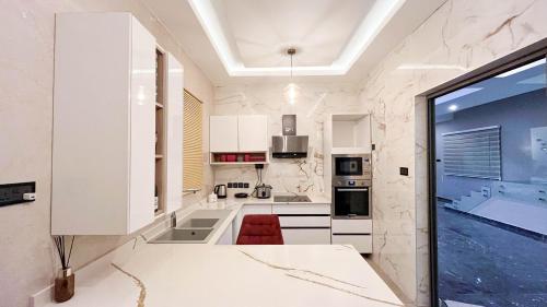 a kitchen with white cabinets and a large window at Sydney’s villa in Accra