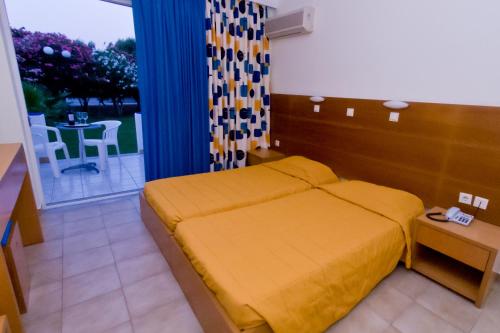 a bedroom with a bed and a table with a patio at Hotel Tigaki's Star in Tigaki
