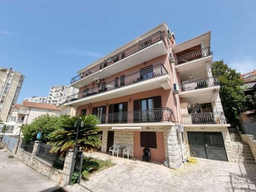 un edificio de apartamentos con una palmera delante en Julija 1 en Igalo