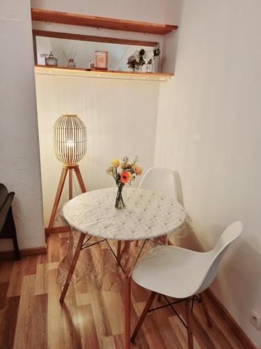 une table et une chaise avec un vase de fleurs dans l'établissement Apartement Lille, à Lille