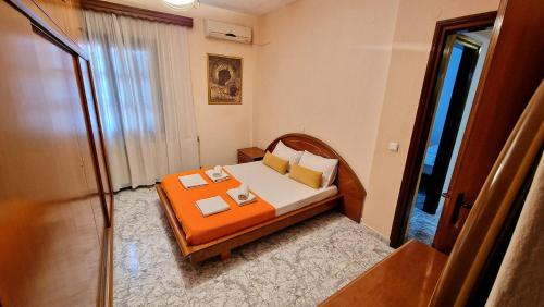 a small bedroom with a bed with an orange bedspread at Fani apartment in Ouranoupoli