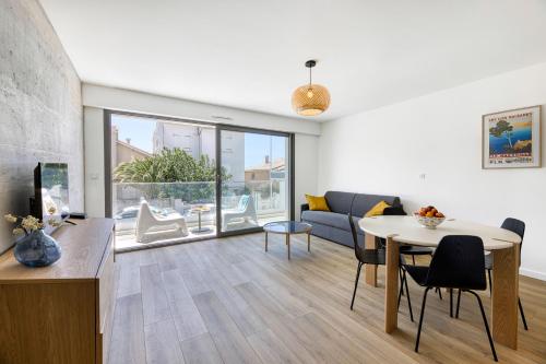 sala de estar con mesa y sofá en Superbe T2 neuf haut de gamme, climatisé, parking gratuit, 2eme ligne balcon, jardin en Carnon-Plage
