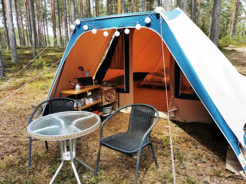 een tent met een tafel en stoelen ervoor bij Volledig ingerichte tent op natuurcamping in Gräsmark