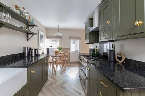 una cucina con armadi verdi e una sala da pranzo di Farriers Cottage-Tranquil Haven, Central Location! a Hexham