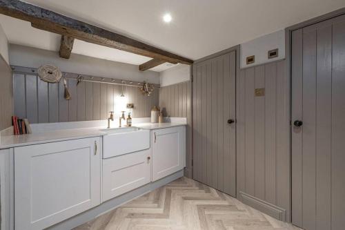baño con armarios blancos y lavabo blanco en Farriers Cottage-Tranquil Haven, Central Location! en Hexham
