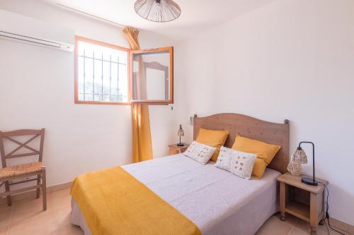 1 dormitorio con 1 cama con sábanas amarillas y ventana en Capra Scorsa - Appt vue mer et piscine partagée, en Belgodère