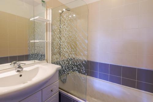 y baño con ducha, lavabo y espejo. en Capra Scorsa - Appt vue mer et piscine partagée, en Belgodère