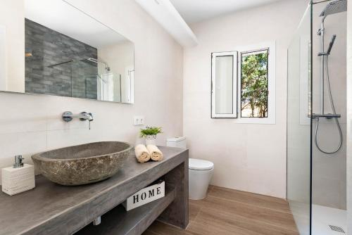 a bathroom with a stone sink and a shower at Villa Bini Uxuanne in Binibeca