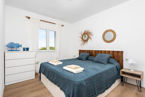 a white bedroom with a blue bed and a window at Villa Bini Uxuanne in Binibeca