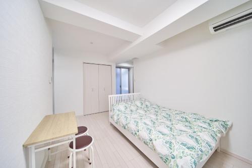 - une chambre blanche avec un lit et un bureau dans l'établissement Yuzuki Dome Osaka Kujo, à Osaka
