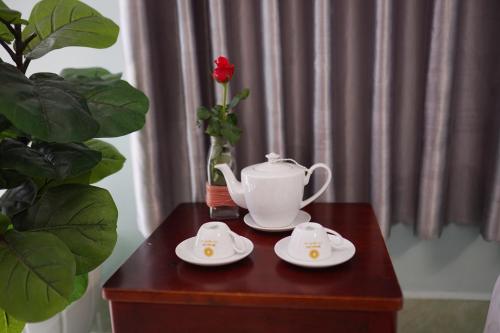 a tea pot and saucers on a table with a plant at THANH THẢO MOTEL in Vung Tau