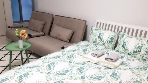 a bedroom with a bed with a couch and a chair at Yuzuki Dome Osaka Kujo in Osaka