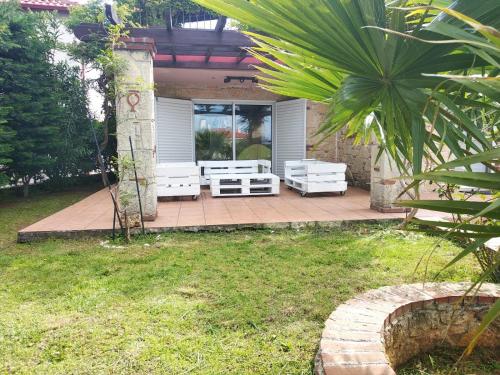 a patio with white benches on a patio at Naturstein-Mediterranhaus mit Gartenblick in Flogita