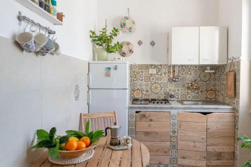 ~ ~ Brezza Mediterranea ~ ~ في بونسا: مطبخ مع طاولة خشبية مع وعاء من البرتقال