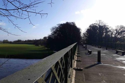 a bridge over a river next to a park at The CowShed Cottage - Beautiful Location in Lancaster
