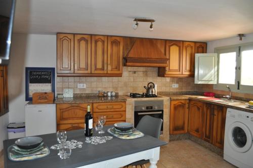 eine Küche mit Holzschränken und einem Tisch mit Weingläsern in der Unterkunft La Estrellita in Iznájar