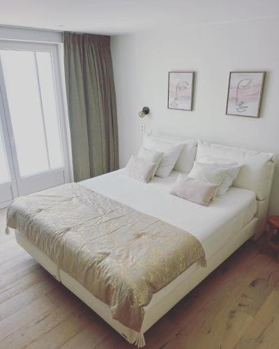 Mina en Family Bed and Breakfast في Meise: غرفة نوم بسرير كبير عليها شراشف ووسائد بيضاء