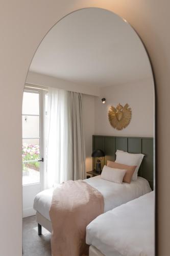 a bedroom with two beds and a mirror at Hôtel Le Prieuré in Paray-le-Monial