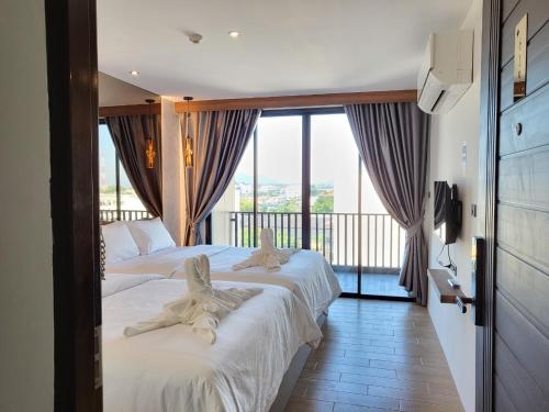 two beds in a hotel room with a balcony at S3 Huahin Hotel in Hua Hin