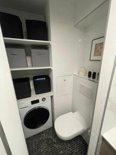 uma pequena cozinha branca com um WC e uma máquina de lavar roupa em Le LihamWood em Megève