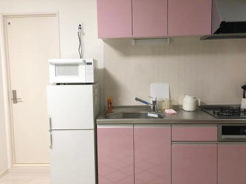 a kitchen with a white refrigerator and a microwave at Yuzuki Dome Osaka Kujo in Osaka